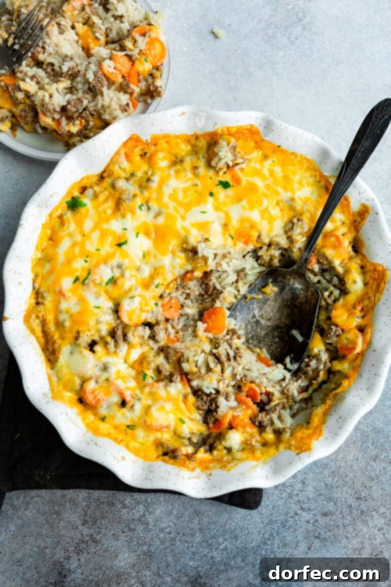 Hearty Cheesy Beef and Rice Bake 7 a photo of a white circular ceramic baking dish full of cheesy ground beef and rice caserrole.