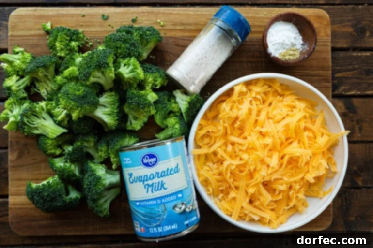 A flat lay photograph showcasing the seven key ingredients for the creamy cheese sauce: a block of sharp cheddar, evaporated milk, cornstarch, ground mustard, salt, and black pepper, ready for preparation.