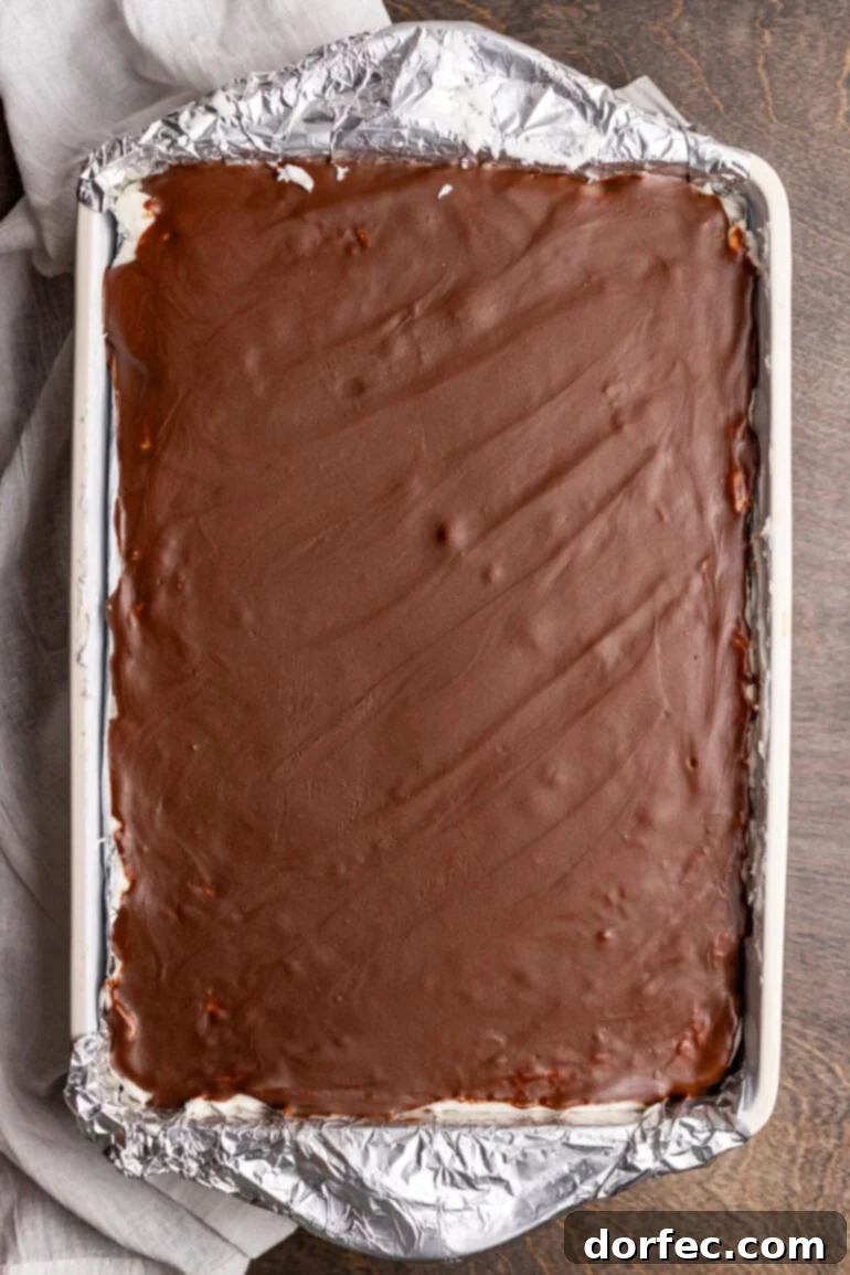 A 9x13 inch baking pan full of baked peppermint brownies topped with a glossy chocolate glaze, ready for slicing.