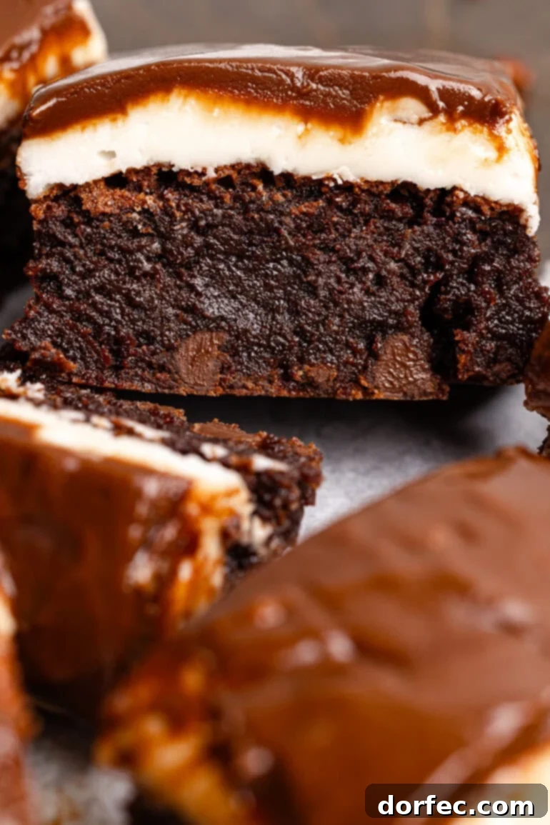 A thick and fudgy chocolate brownie with a white peppermint patty layer, topped with a thin chocolate glaze, showcasing the beautiful layers.