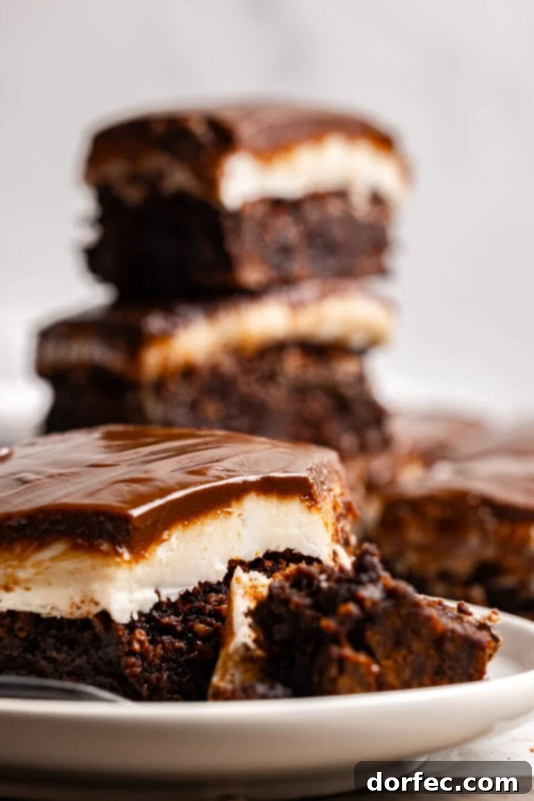 Several homemade peppermint brownies with a white peppermint patty layer topped with a glossy chocolate glaze.