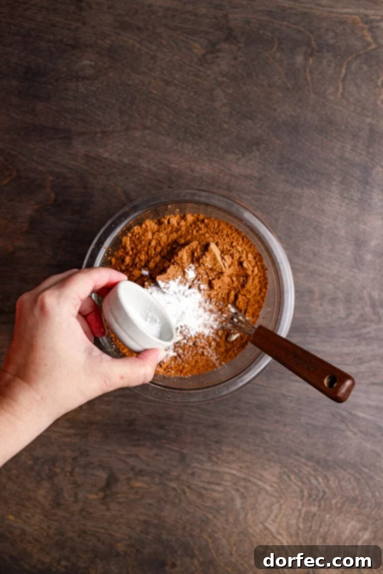 Adding eggs to the wet brownie mixture.