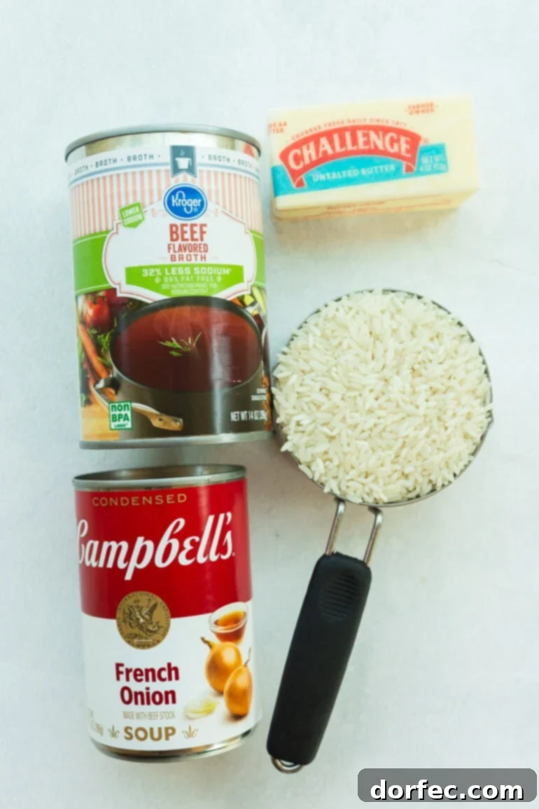 All the ingredients laid out on a counter: long-grain white rice, a stick of butter, a packet of onion soup mix, and a can of beef broth. Simple pantry staples that come together to make a rich, cozy side dish.