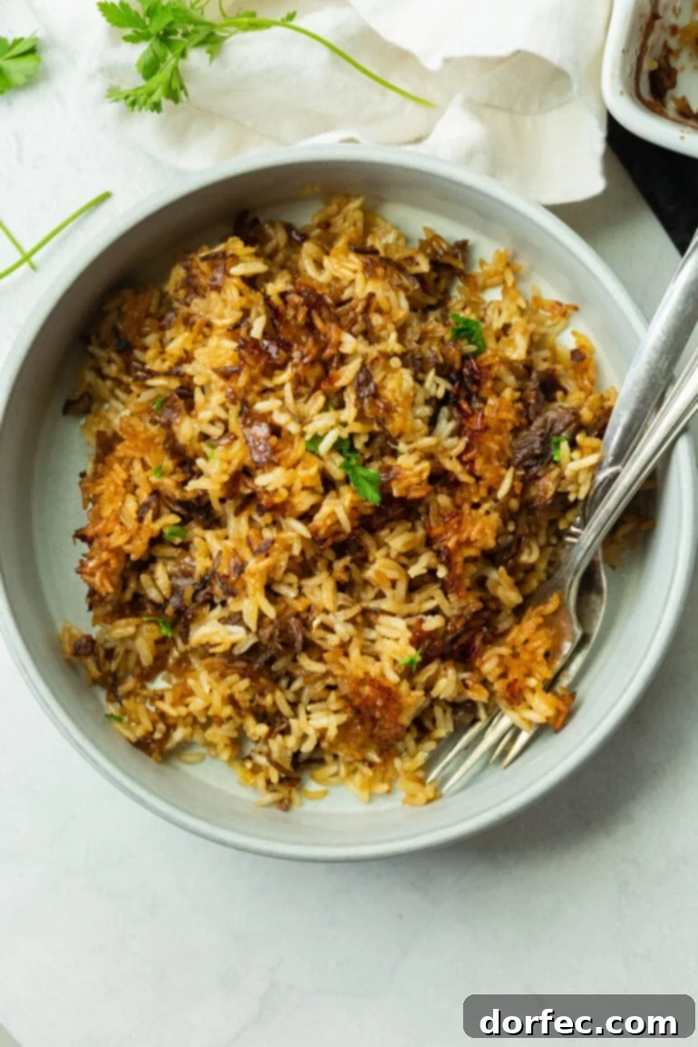 A close-up angle of the baked rice served in a bowl with two forks, showing the glossy, buttery finish and golden-brown edges. You can see the texture clearly, soft, crispy, savory, and packed with flavor.