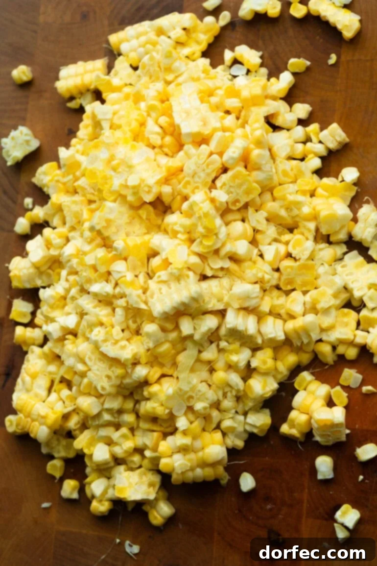 Velvety Creamed Corn Made Simple 2 Fresh cut corn kernels neatly arranged on a rustic wooden cutting board, emphasizing the quality of ingredients.