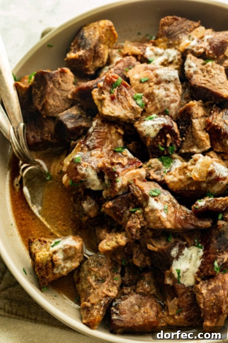 Effortless Garlic Butter Slow Cooker Steak Bites 4 A large, inviting bowl filled with succulent steak tips, glistening in a rich garlic butter sauce, generously topped with fresh chopped parsley.
