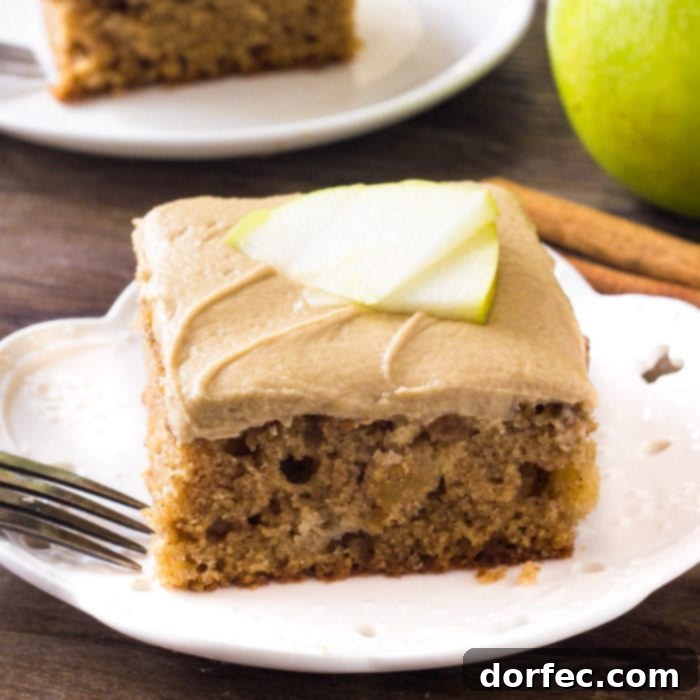 A slice of moist apple cake generously topped with rich caramel frosting, embodying autumn's sweetest flavors