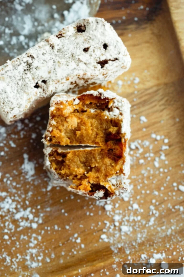 A close-up shot of a Chubby Hubby Peanut Butter Bar, broken in half to reveal its gooey, chewy, peanut butter-infused interior and graham cracker texture. Dusted with powdered sugar.
