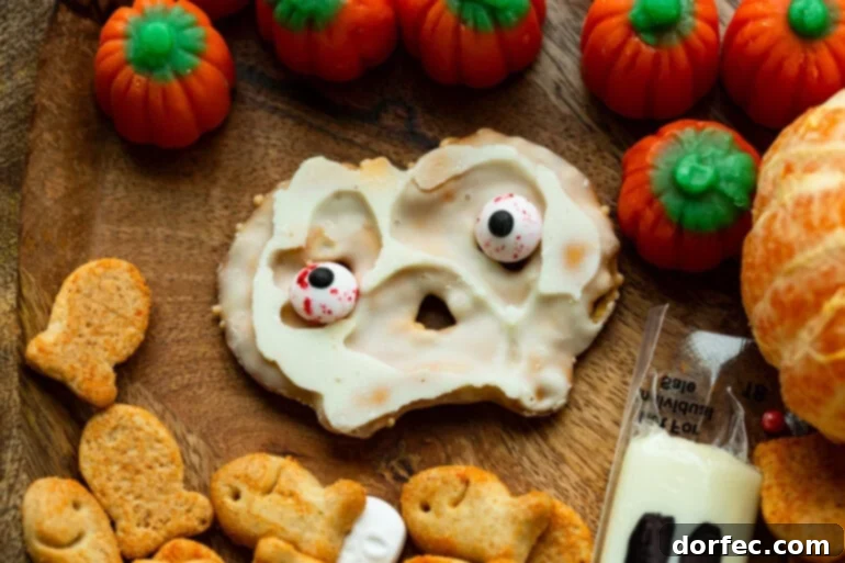 A white chocolate-covered pretzel crisp with edible googly eyes stuck on it, showcasing a simple yet effective Halloween snack idea.