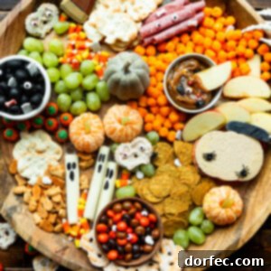 a large circular wooden charcuterie board filled with halloween themed snacks