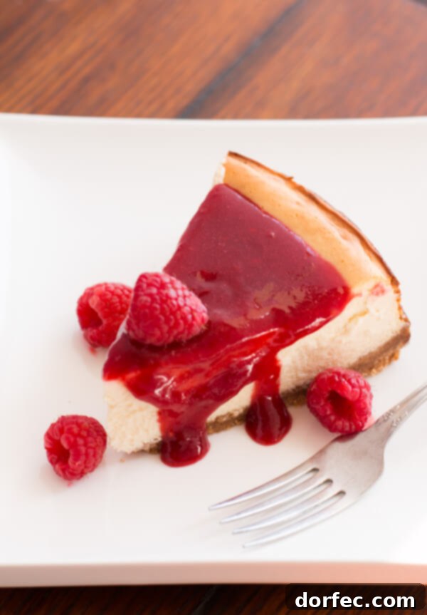 Close-up of the smooth, creamy texture of Greek Yogurt New York Cheesecake with berry sauce.