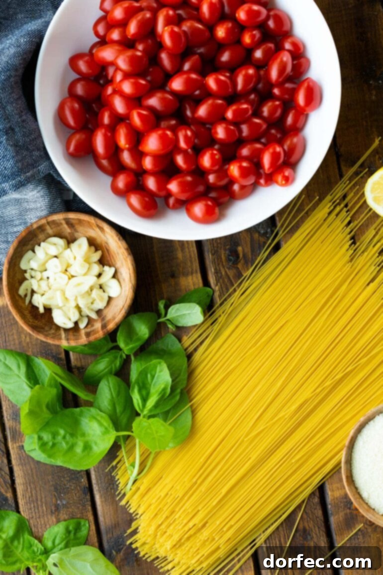 A beautifully arranged flat lay photo of uncooked angel hair pasta noodles, a bowl brimming with ripe cherry tomatoes, a vibrant bunch of fresh basil leaves, and a small bowl of thinly sliced garlic cloves, highlighting the simple ingredients of the dish.