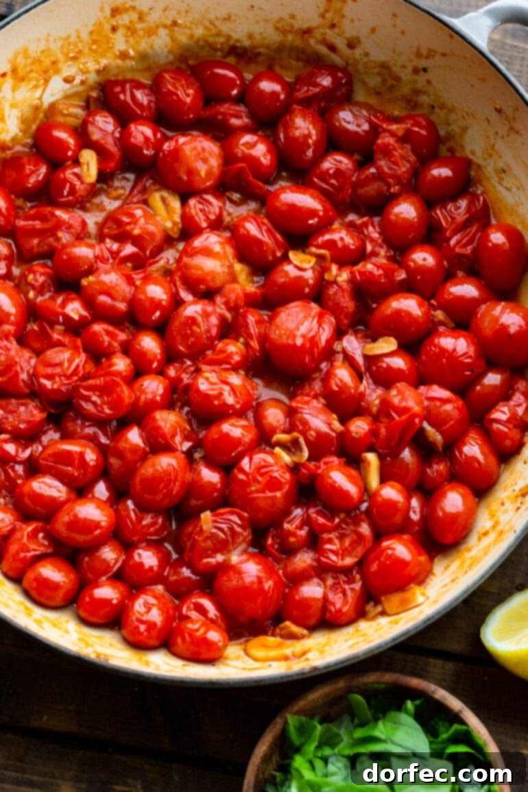 A close-up shot of a pot filled with vibrant cherry tomatoes being sautéed with thinly sliced fresh garlic in olive oil, capturing the initial stage of making the flavorful pasta sauce.