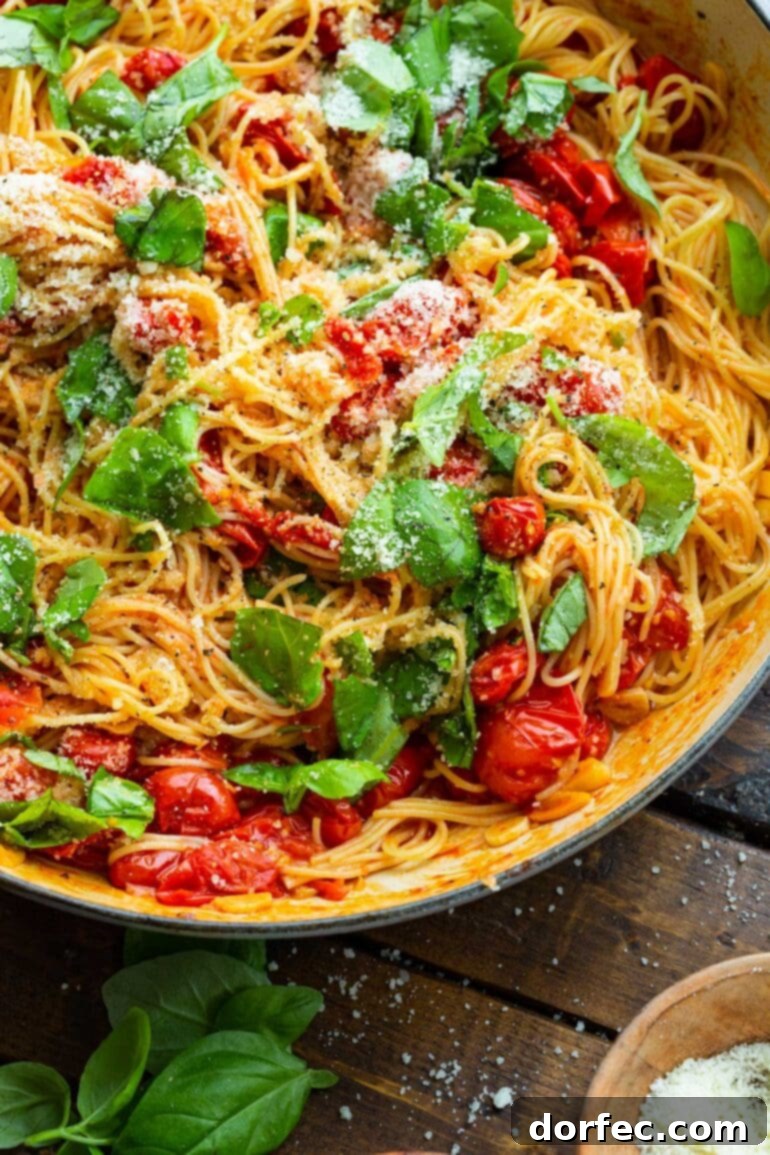 A captivating photo of a large pot filled with perfectly sautéed grape tomatoes and fresh basil leaves, generously tossed with cooked angel hair pasta, capturing the essence of a fresh and fast dinner.