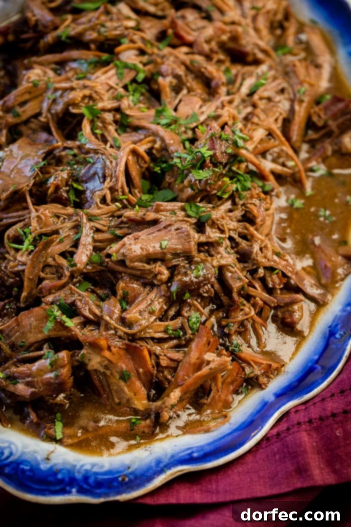 Easy Slow Cooker Mississippi Pot Roast 2 Shredded slow cooker pot roast served in a decorative platter, ready to be enjoyed with its rich, savory juices.