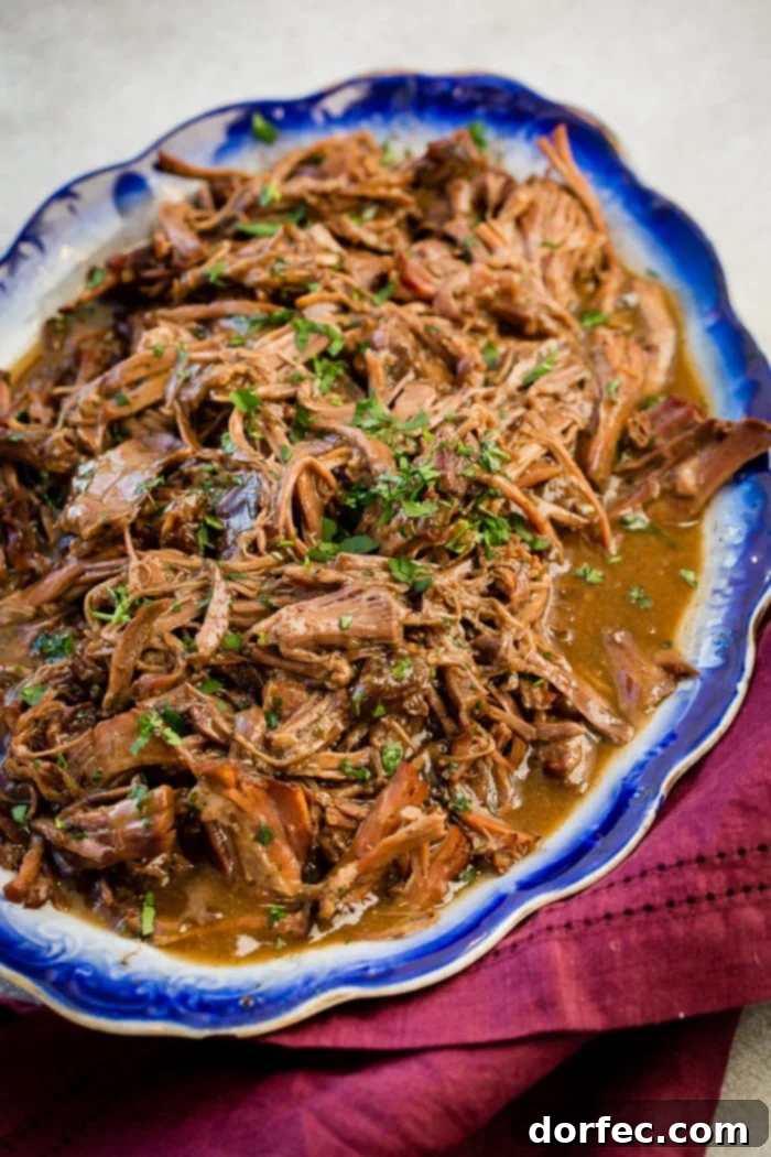 Easy Slow Cooker Mississippi Pot Roast 3 Generous serving of shredded slow cooker Mississippi pot roast in a vibrant blue serving platter, inviting guests to enjoy.