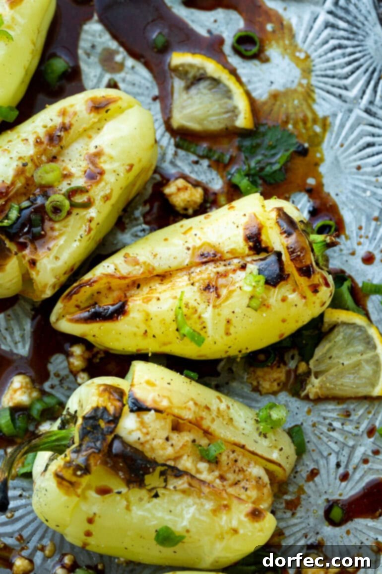 A close-up shot of several charred peppers stuffed with rich, melted cheese, presented on a rustic cutting board.