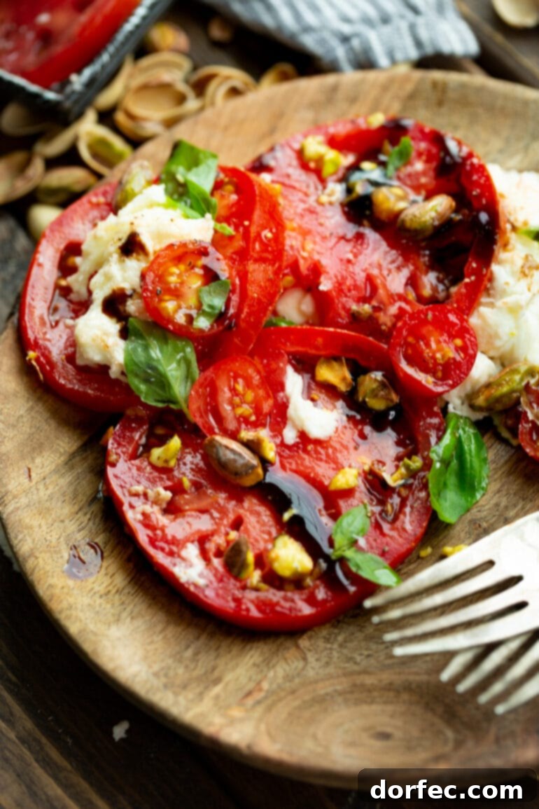 Elevated Caprese Salad with Pistachios 10 A charming photo of a wooden salad plate holding a single, artfully arranged serving of Caprese salad, highlighting its fresh ingredients and elegant presentation.