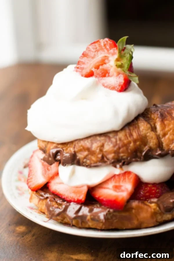 Another perspective of the grilled croissant dessert, showcasing the warm, golden-brown grill marks and the vibrant red strawberries against the dark hazelnut spread.