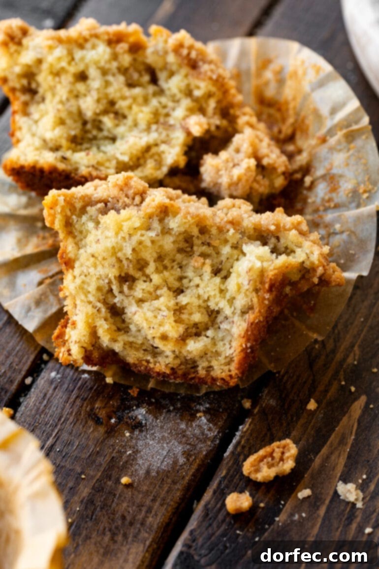 Ultimate Streusel Banana Bread Muffins 3 A banana crumb muffin expertly broken in half, showcasing its incredibly moist, tender interior with visible banana pieces and the delightful crumb topping.