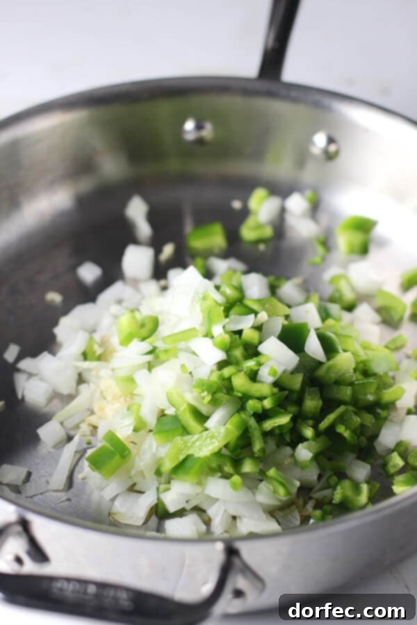 Preparing Healthy One-Pot Chili Mac Ingredients Diced onion and green bell pepper sautéing in a metal skillet, ready for the turkey