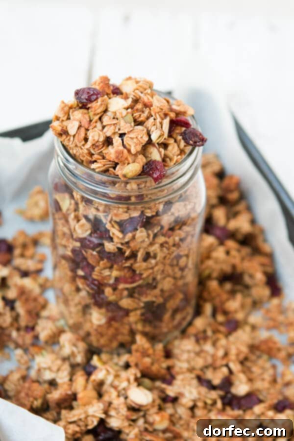 The Secret to the Best Homemade Granola Close-up of golden-brown homemade granola clusters, highlighting the vibrant strawberry craisins and crunchy almond slices.