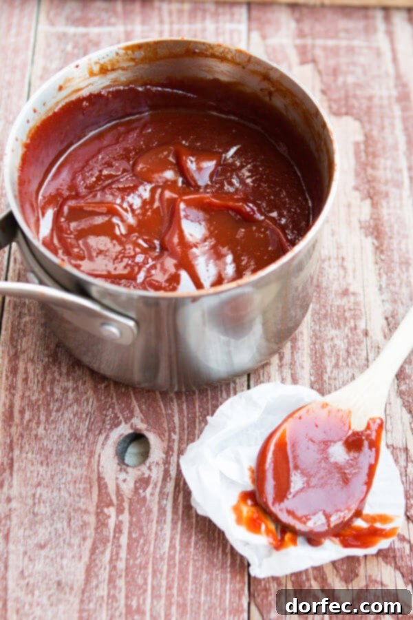 Freshly made homemade BBQ sauce being poured into a mason jar for storage.