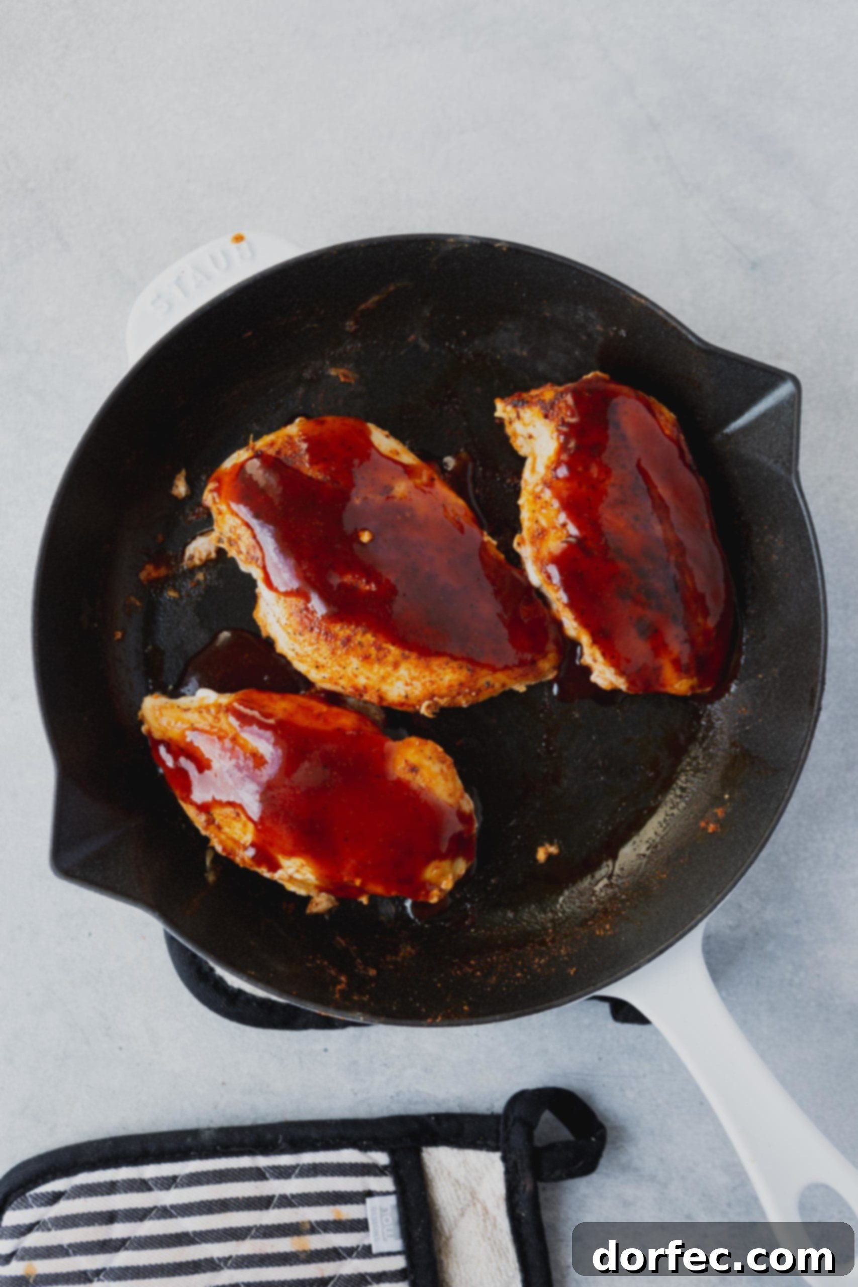 Loaded Cheesy Bacon BBQ Chicken 3 Three partially cooked chicken breasts in a skillet, already brushed with a generous layer of savory BBQ sauce.