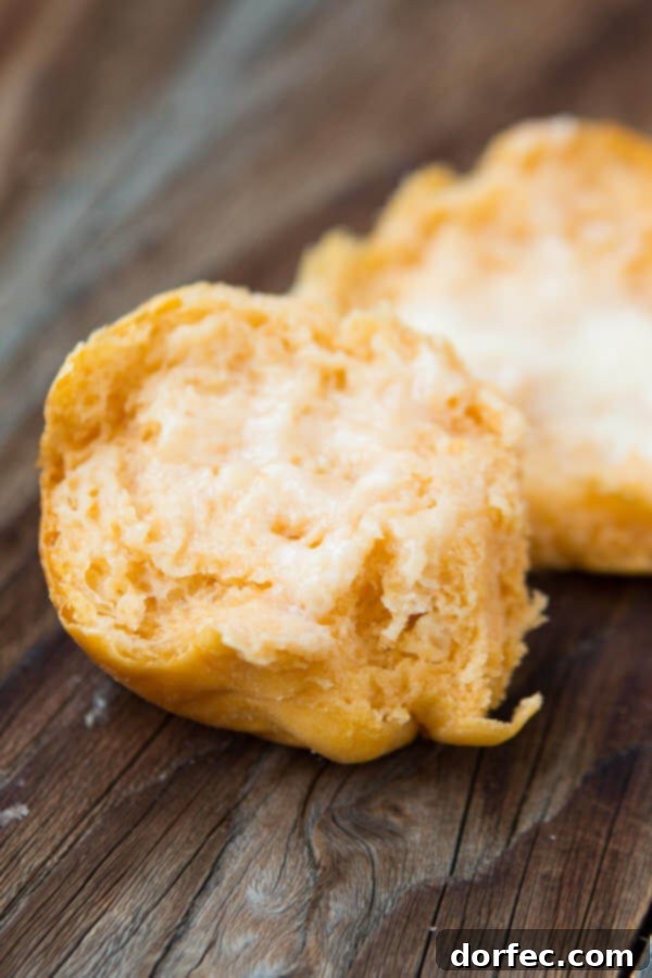 Soft & Fluffy Sweet Potato Dinner Rolls A sweet potato roll sliced in half, revealing its tender, airy crumb and vibrant orange hue.
