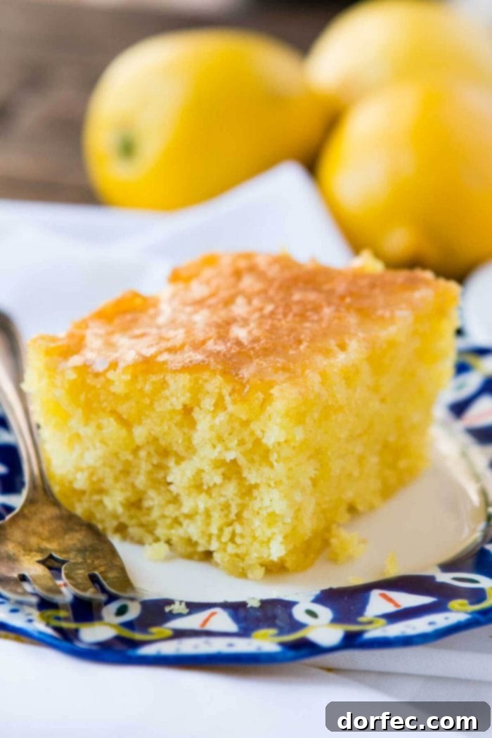 A delightful slice of Lemon Jello Cake resting on a white napkin, accompanied by a silver fork.