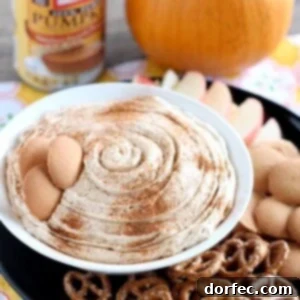 Pumpkin Cheesecake Dip in a white bowl surrounded by pretzels, wafers and sliced apples.