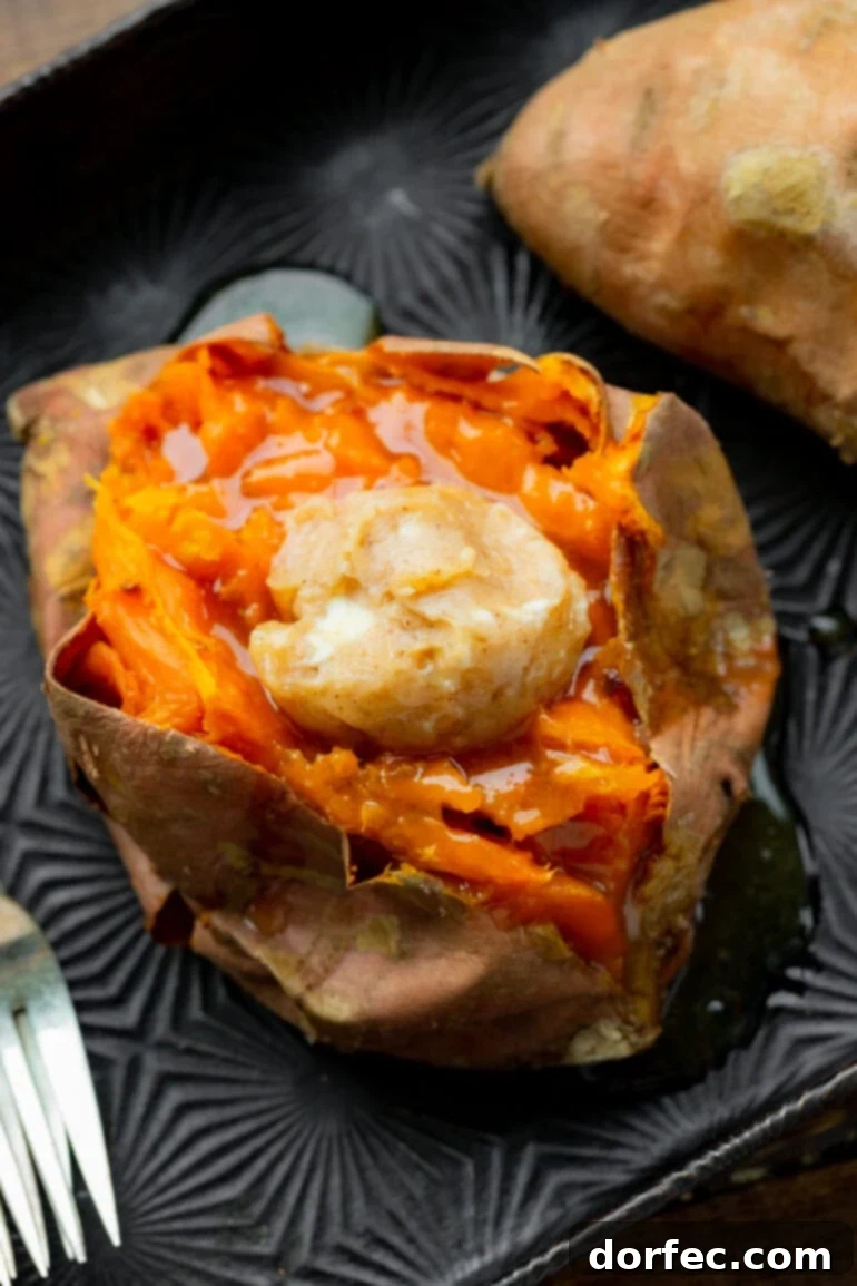 The Ultimate Texas Roadhouse Loaded Sweet Potato at Home 5 A close-up photo of a baked sweet potato sliced open, mashed inside, and topped with a generous dollop of cinnamon honey butter, ready for more toppings.