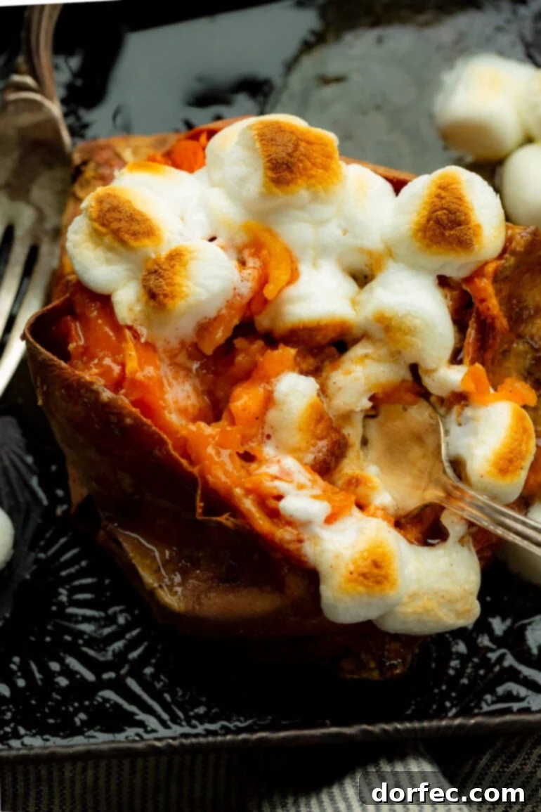 The Ultimate Texas Roadhouse Loaded Sweet Potato at Home 7 A photo of a fork digging into a baked sweet potato topped with roasted mini marshmallows, showcasing its gooey texture and inviting appeal.