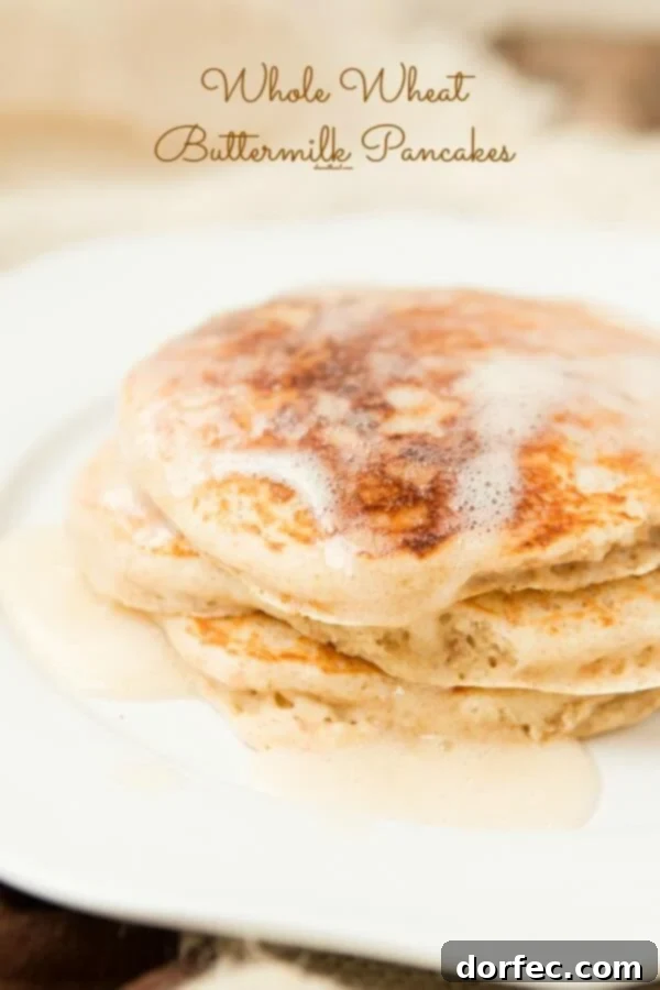 Fluffy whole wheat buttermilk pancakes served with berries and syrup on a breakfast plate
