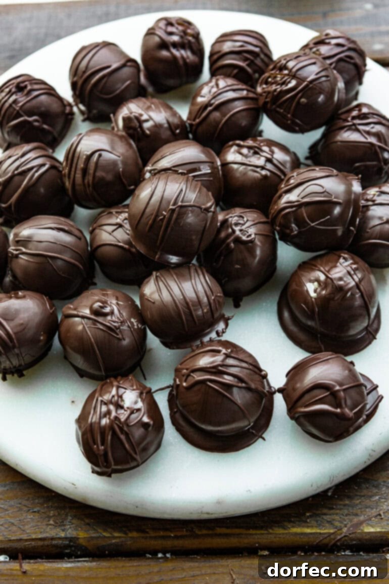 A photo of several dark chocolate-covered peanut butter balls sitting on a elegant white serving platter.