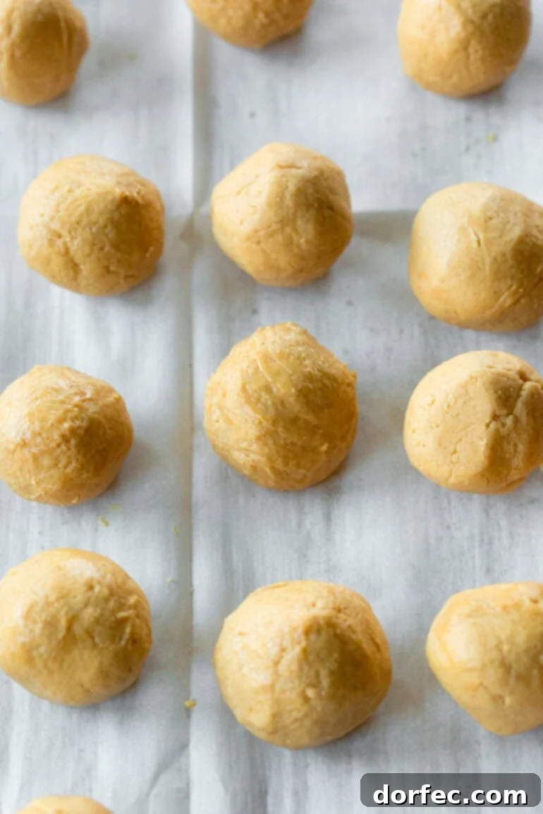 A photo of several pre-dipped peanut butter truffle balls arranged neatly on a piece of parchment paper, ready for their chocolate coating.