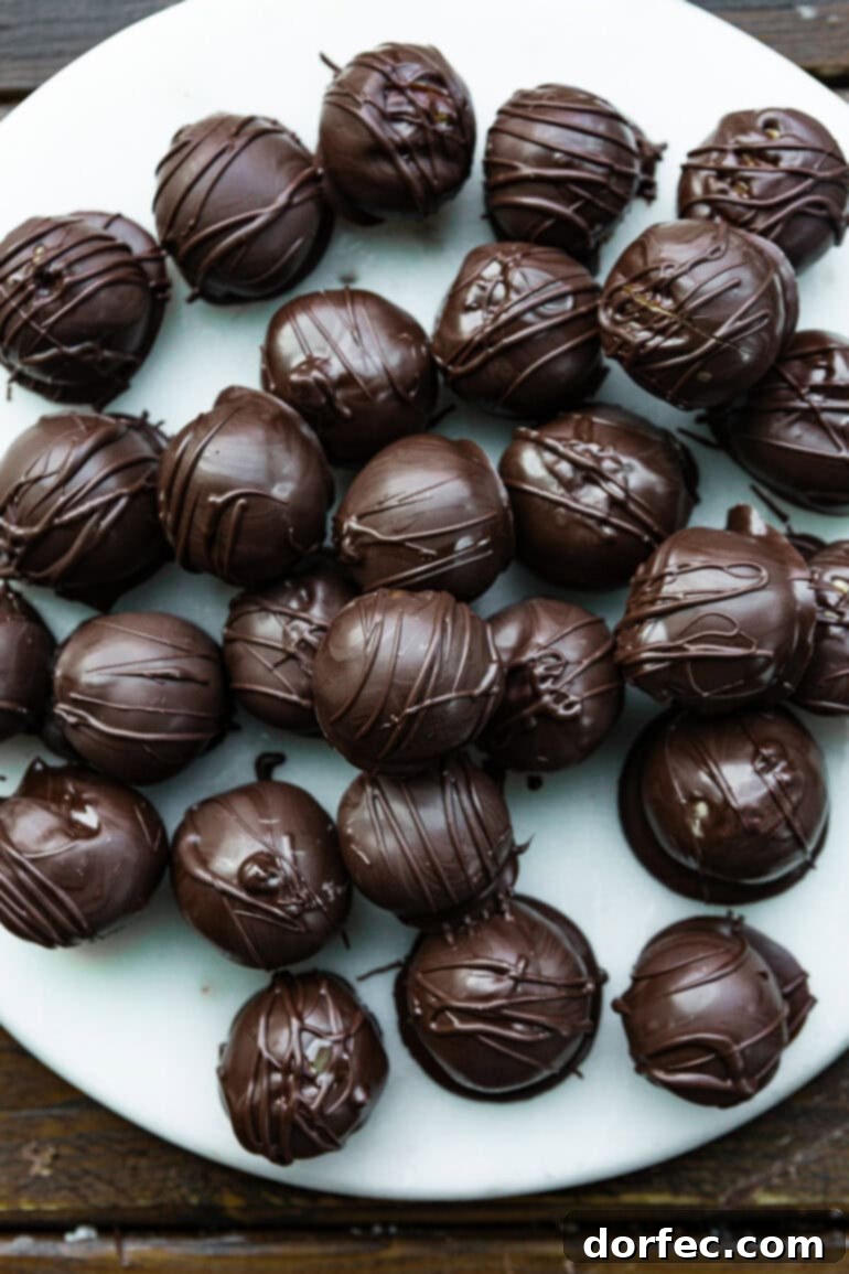 A photo of several perfectly rounded chocolate-covered peanut butter truffles arranged on a white serving dish.