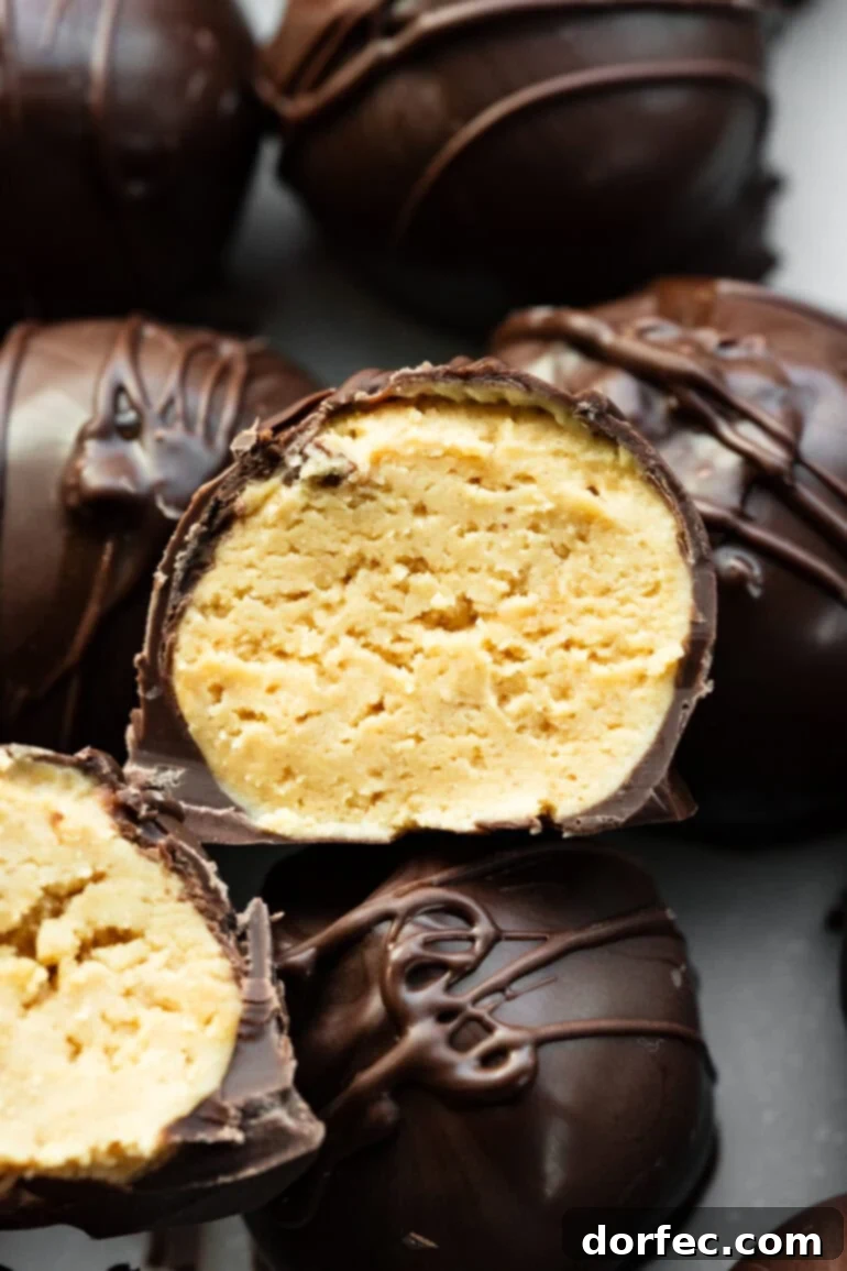 A close-up photo of a peanut butter truffle coated in dark chocolate, sliced in half to show the creamy interior.