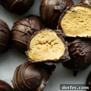 A photo of several dark chocolate-covered peanut butter balls, with two sliced in half revealing the creamy peanut butter inside.