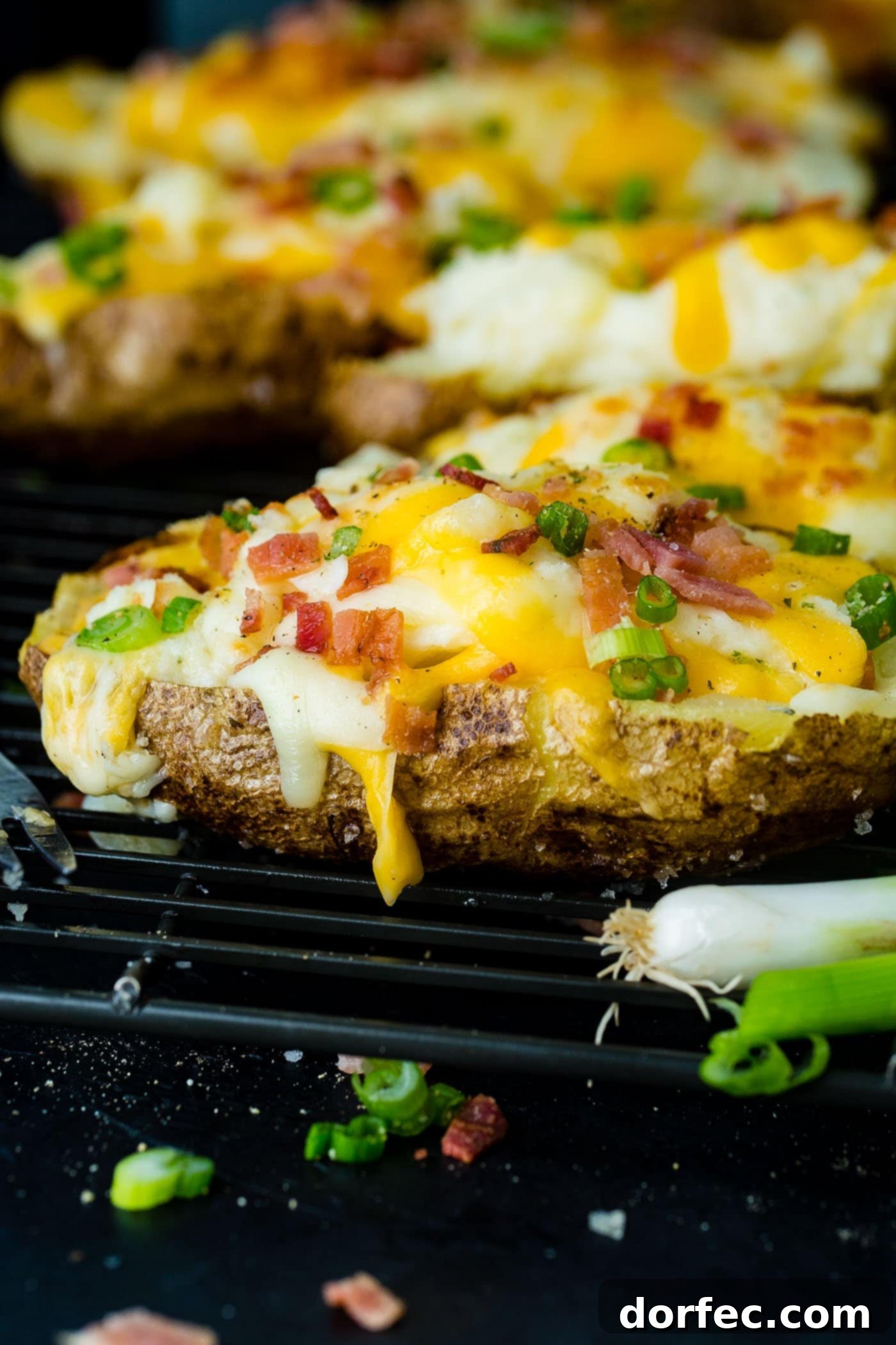 A cooling rack showcasing perfectly cheesy topped twice baked potatoes with golden, crispy bacon crumbles