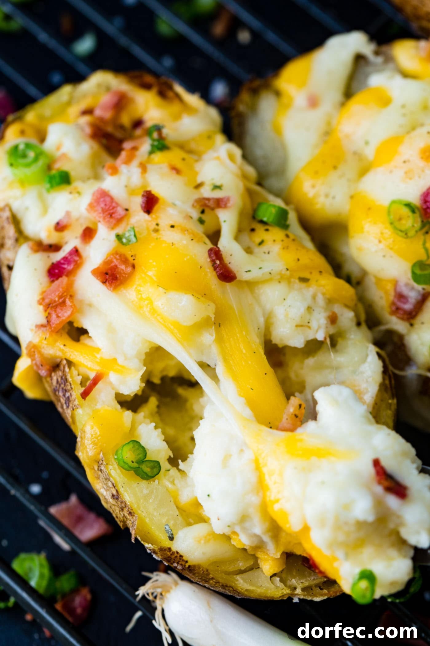 A beautifully arranged cooling rack with a series of loaded twice baked potatoes, showcasing the rich, melted cheese and crisp bacon topping