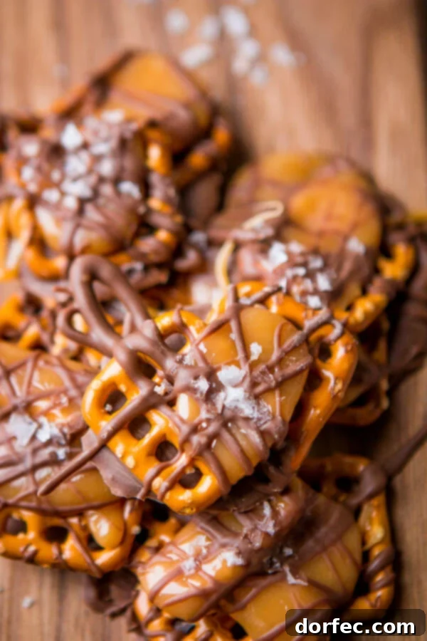 A close-up shot of freshly made salted caramel pretzel snaps, showing melted chocolate, caramel, pretzels, and a sprinkle of sea salt.