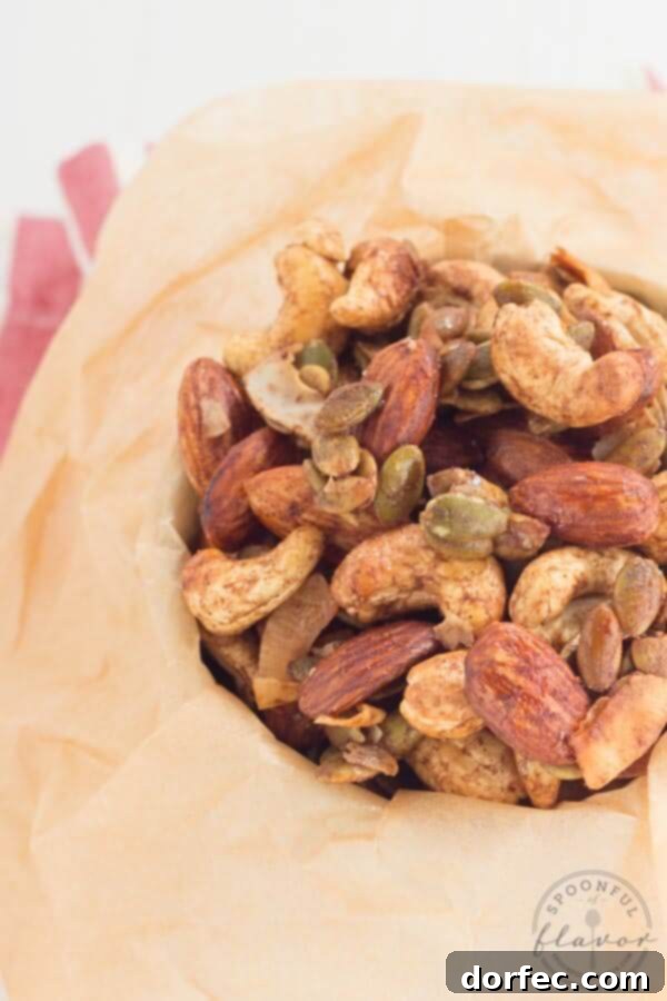 Hand reaching for a handful of homemade Spiced Trail Mix from a bowl.