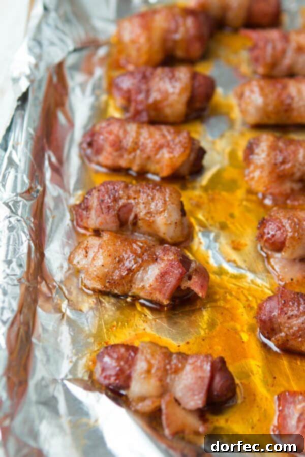 The Best Bacon-Wrapped Little Smokies Recipe for Parties and Game Day Close-up of golden-brown bacon-wrapped little smokies on a foil-lined baking tray, ready to serve.