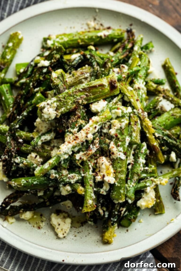 Zesty 5-Minute Lemon Feta Grilled Asparagus 2 A vibrant photo of grilled asparagus spears tossed with crumbled feta cheese and lemon zest on a serving plate, ready to be enjoyed.
