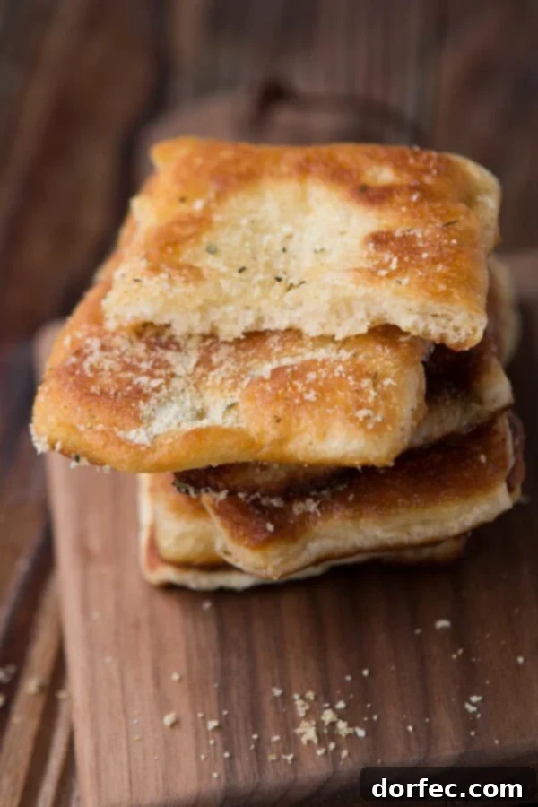 Golden-brown Easy Garlic Parmesan Fry Bread, fresh out of the oil, sprinkled with cheese and garlic seasoning.