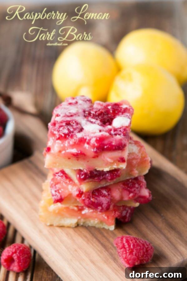 A close-up shot of several Raspberry Lemon Bars, showcasing their thick, golden crust and vibrant pink filling, stacked on a rustic wooden board.
