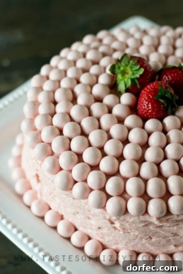 Layers of vanilla malt cake and strawberry buttercream in a slice of Strawberry Malted Milkshake Cake