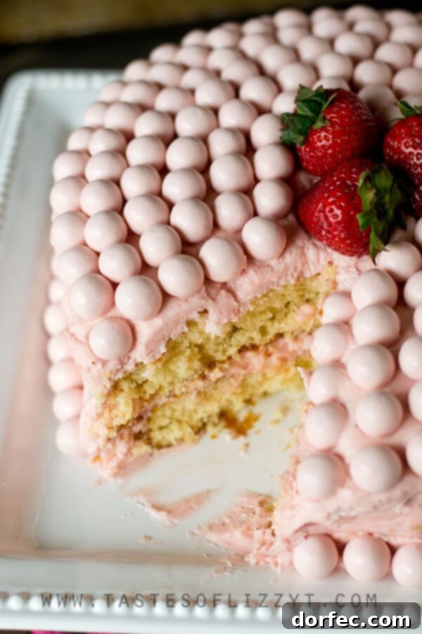 Strawberry Malted Milkshake Cake frosted with pink buttercream and adorned with Whoppers