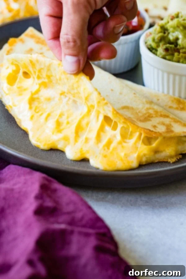 A delectable cheese quesadilla on a plate, with one side lifted to reveal the wonderfully gooey, melted cheese within.